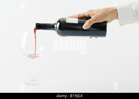 Man gießt Rotwein aus der Flasche, Ansicht von Hand abgeschnitten Stockfoto