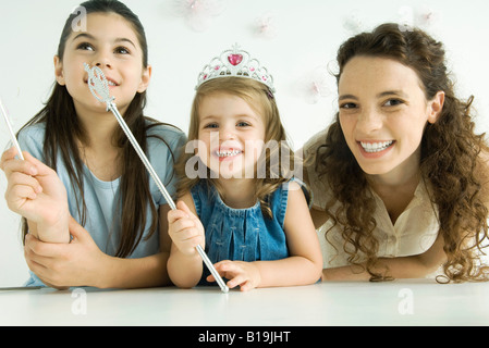 Mutter und zwei Töchter, lächelnd in die Kamera, jüngere Mädchen trägt Tiara und Holding-Zauberstab Stockfoto