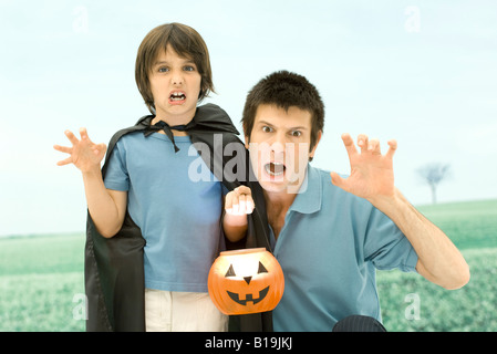 Vater und Sohn halten Jack o' Lantern, furchterregende Gesichter in die Kamera machen Stockfoto