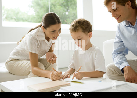 Kleiner Junge mit seinen Hausaufgaben zu helfen Eltern Stockfoto