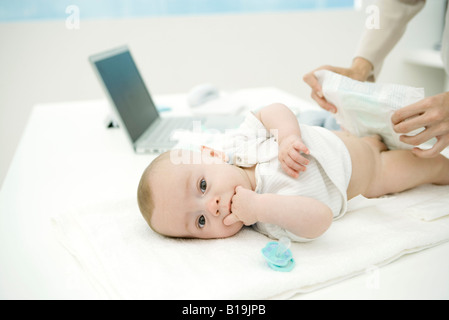 Mutter von wechselnden Babywindel auf Schreibtisch, Laptop im Hintergrund Stockfoto