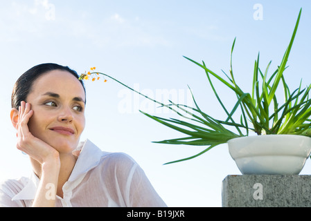 Frau mit Topfpflanze, lächelnd, niedrigen Winkel Ansicht Stockfoto