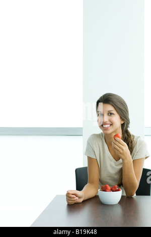 Teen Mädchen essen Erdbeeren, lächelnd in die Kamera Stockfoto