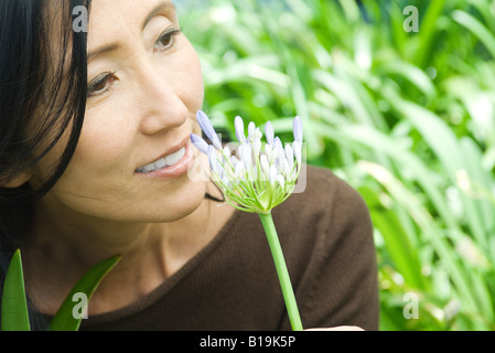 Frau riechen Schmucklilie, Lächeln, wegschauen Stockfoto