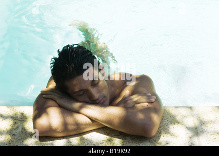 Man ruht Kopf auf Arme auf Seite des Schwimmbad, Augen geschlossen Stockfoto