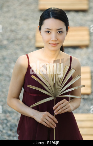 Frau mit getrockneten palm Leaf, lächelnd in die Kamera Stockfoto