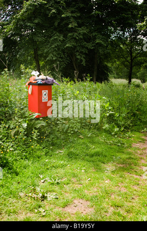 Sehr stinkende und überquellenden Hundeabfallbehälter neben einem Fußweg auf dem Lande Stockfoto