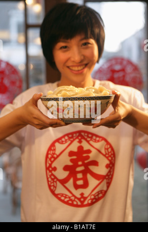 Junge Chinesin hält eine Schale mit chinesischen Knödel Stockfoto