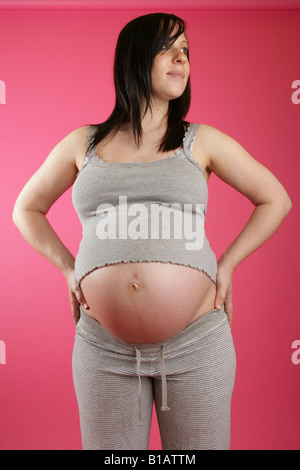 Ein Kopf auf Blick auf einen dunklen Haaren 38 Woche (neun Monate) schwangere Frau stehend tragen legere Kleidung grau. Stockfoto