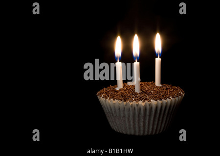Ein Cupcake mit drei Kerzen in der Dunkelheit Stockfoto
