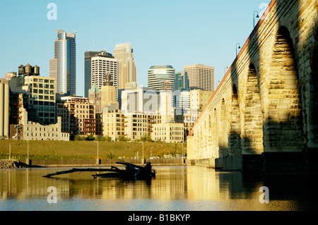 die Skyline von Minneapolis in der Morgendämmerung über dem Mississippi Fluß mit den Stein-Bogen-Brücke in das Forground aus betrachtet Stockfoto