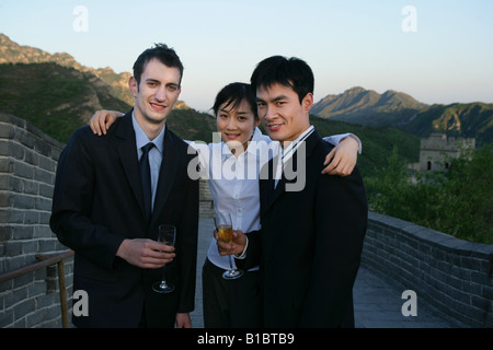 zwei Geschäftsleute und eine Unternehmerin stehen und halten Weingläser auf chinesische Mauer, Peking, China Stockfoto