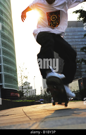 junger Mann auf dem Platz neben Büro Gebäude, Peking, China, Close-Up Skateboard Stockfoto