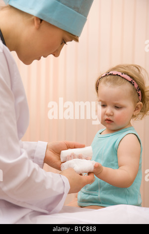 Arzt Kinderarzt, einen Verband auf ein kleines Mädchen-arm Stockfoto