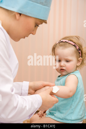 Arzt Kinderarzt, einen Verband auf ein kleines Mädchen-arm Stockfoto