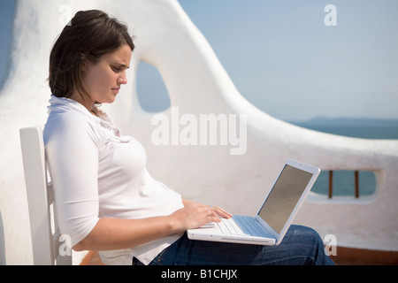 Junge Frau schreiben auf ihrem Macbook Laptop in eine mediterrane Terrasse im Casapueblo Punta del Este-Uruguay Stockfoto