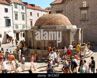 Touristen an einem Brunnen auf dem Hauptplatz in der Altstadt von Dubrovnik, Kroatien Stockfoto