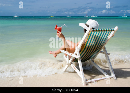 Frau mit Cocktail sitzt in einem Klappstuhl am Strand, Urlaub, Philippinen Stockfoto