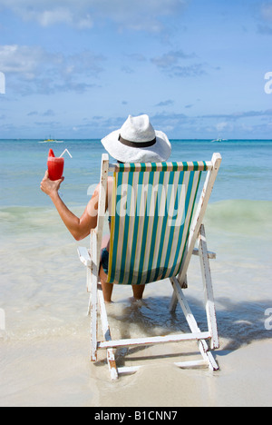 Frau mit Cocktail sitzt in einem Klappstuhl am Strand, Urlaub, Philippinen Stockfoto