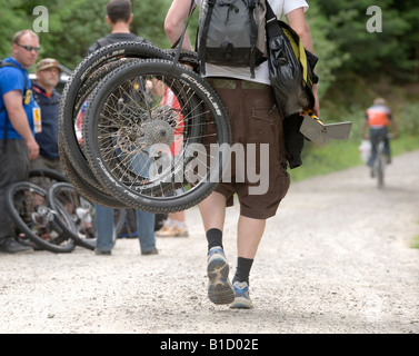 Fahrradmechaniker trägt Ersatzräder für einer der Fahrer bei der UCI Mountain Bike Weltcup Langlauf. Stockfoto