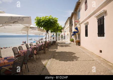 Moscenicka Draga Istrien Kroatien Cafe mit Menschen sitzen an Tischen mit Sonnenschirmen draußen auf schmalen Strasse am Meer Strand Stockfoto