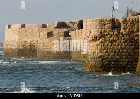 Fischer seine Netze zu sammeln, wie die Sonne am Fuße des die Zinnen des alten Kreuzfahrer Stadt Akko (Akko), Israel Stockfoto