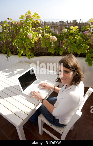 Junge Frau schreiben auf ihrem Macbook Laptop in eine mediterrane Terrasse im Casapueblo Punta del Este-Uruguay Stockfoto