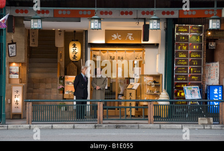 Kyoto, Japan. Zwei Männer, die außerhalb einer Gaststätte auf Shijo Street im Stadtteil Gion Stockfoto