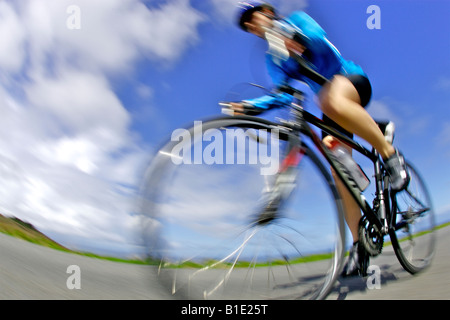 Eine weibliche Radsportler schnell entlang der Küstenstraße in Cornwall auf einem Rennrad Stockfoto