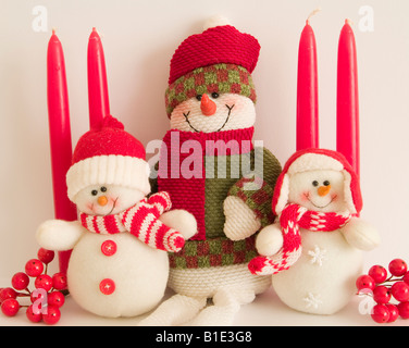 Drei Schneemänner nebeneinander mit einer Anordnung von Kerzen und Beeren Stockfoto