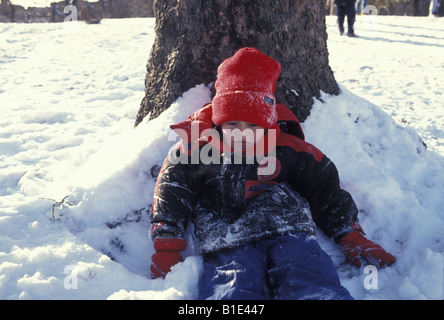 Junge nimmt eine Auszeit an einem Baum an einem hellen Wintertag im Prospect Park Brooklyn New York Stockfoto