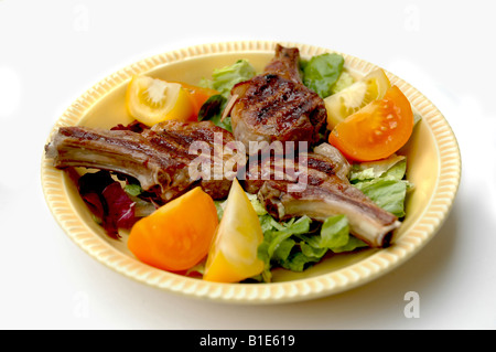 Lampe Koteletts auf einem Salatbett mit Tomatenscheiben Stockfoto