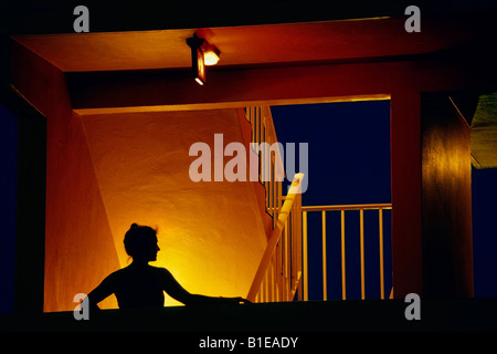 Frau im Abendkleid stehen im beleuchteten Treppenhaus @ Nacht USA Stockfoto