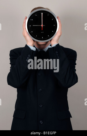 Geschäftsmann hält eine Uhr vor Gesicht Stockfoto
