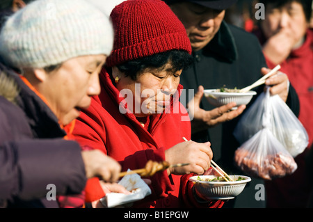 China Beijing Chinese New Year Spring Festival Changdian street fair ältere Frauen essen Nudeln Stockfoto