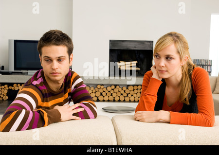 Junger Mann stützte sich auf eine Couch mit einer jungen Frau, die ihn ansah Stockfoto