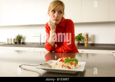 Teller mit Reis vor einer jungen Frau gelehnt eine Küchentheke Stockfoto