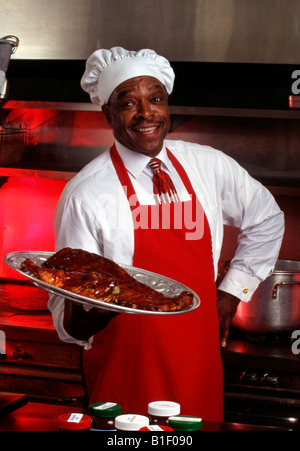 Porträt eines afroamerikanischen Geschäftsmannes in Chefhut mit Barbebue-Rippen Stockfoto