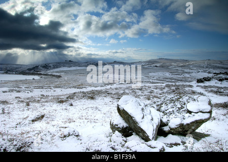 Starker Schneefall in der Nähe von Chinkwell Tor auf Dartmoor National Park mit zwei Granitfelsen im Vordergrund und einen stürmischen Himmel Stockfoto