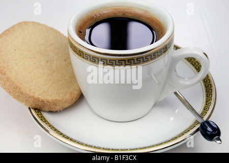 Espresso, Kaffee schwarz in einer kleinen Kaffeetasse mit Shortbread Keks und Kaffee Bohnen-Löffel Stockfoto