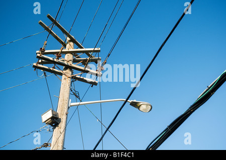 Telefonmast mit Drähten und Straßenlaterne gegen reiche blauen Himmel. Stockfoto