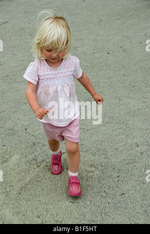 Stock Foto eines blonden Haaren zwei Jahre alten Mädchens laufen und springen auf dem Spielplatz-Platz Stockfoto