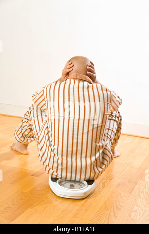 Afrikanischer Mann sitzt im Maßstab Stockfoto