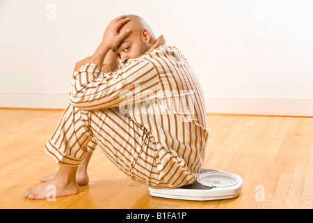 Afrikanischer Mann sitzt im Maßstab Stockfoto