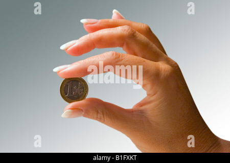 Weibliche Hand, die eine-Euro-Münze Stockfoto