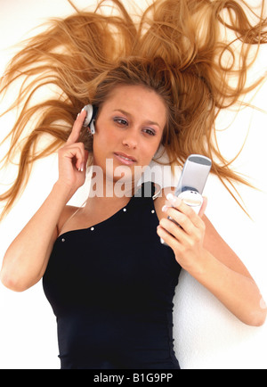 Junge Frau trägt Kopfhörer und Handy halten, Draufsicht Stockfoto