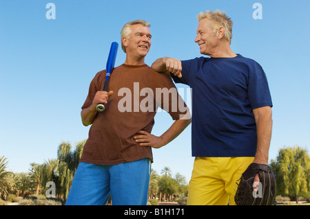 Ältere Mann mit Baseball Handschuh stützte sich auf Mann mit Baseballschläger, im freien Stockfoto