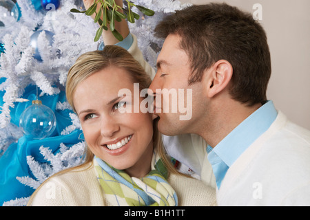 Mann, die Frau unter Mistelzweig küssen Stockfoto