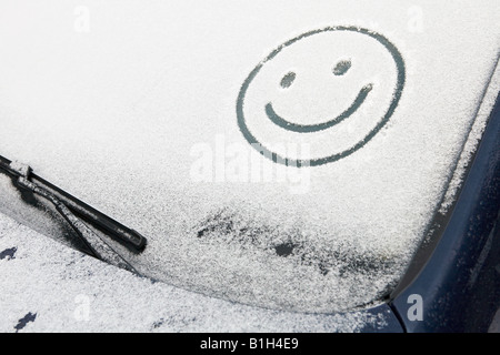 Smiley-Gesicht im Schnee auf dem Auto Stockfoto