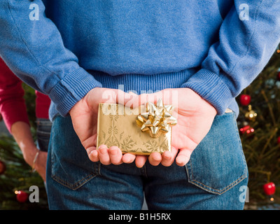 Man versteckt sich ein Weihnachtsgeschenk hinter Rücken Stockfoto